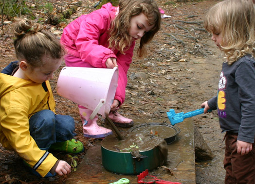 3 meisjes spelend met zand, water, steentjes en takjes